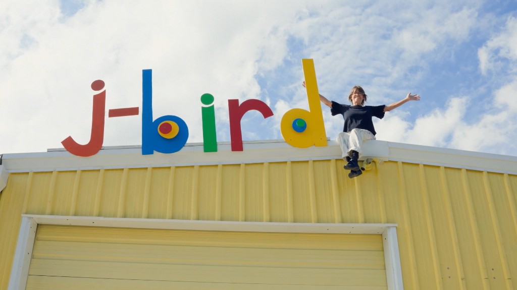 J-Bird sitting on the rooftop beside the colorful j-bird sign