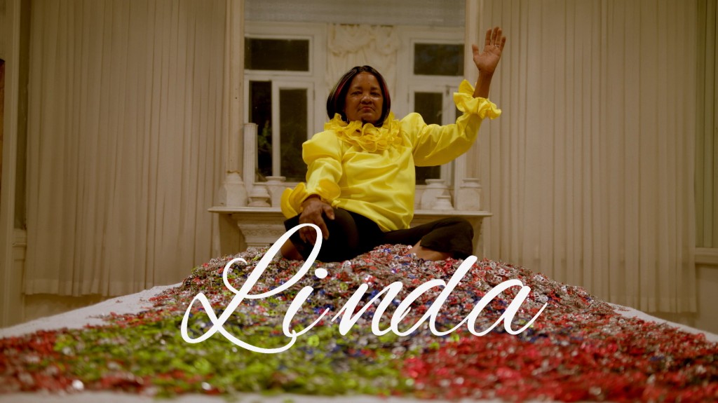 Linda in a yellow blouse sitting amid a pile of pull-tabs