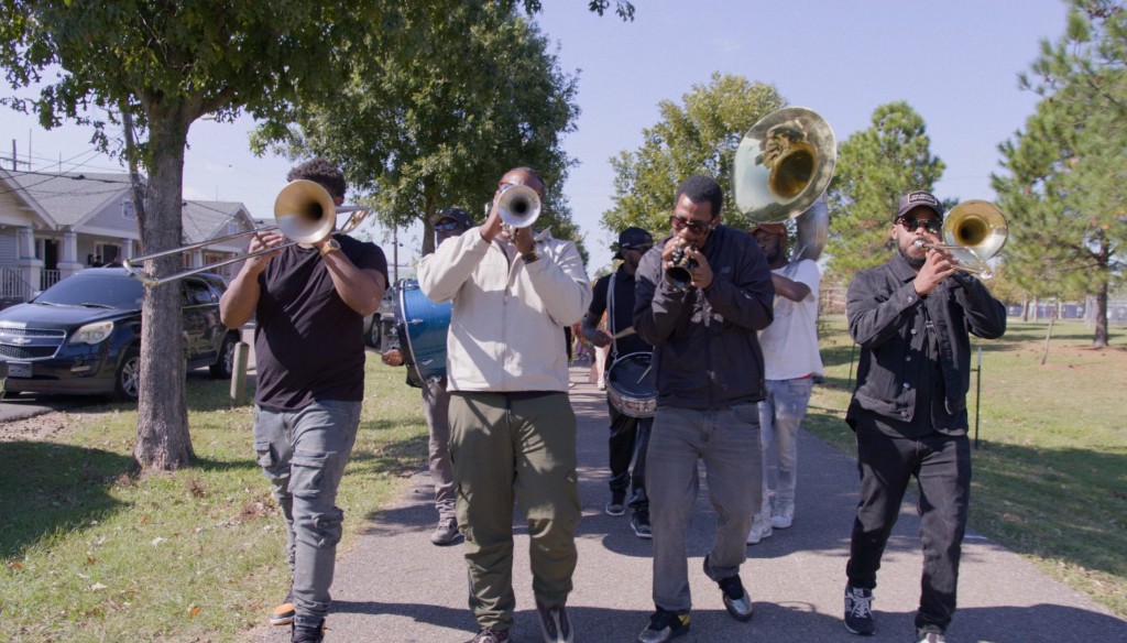 Brass band marching and playing down a neighborhood path